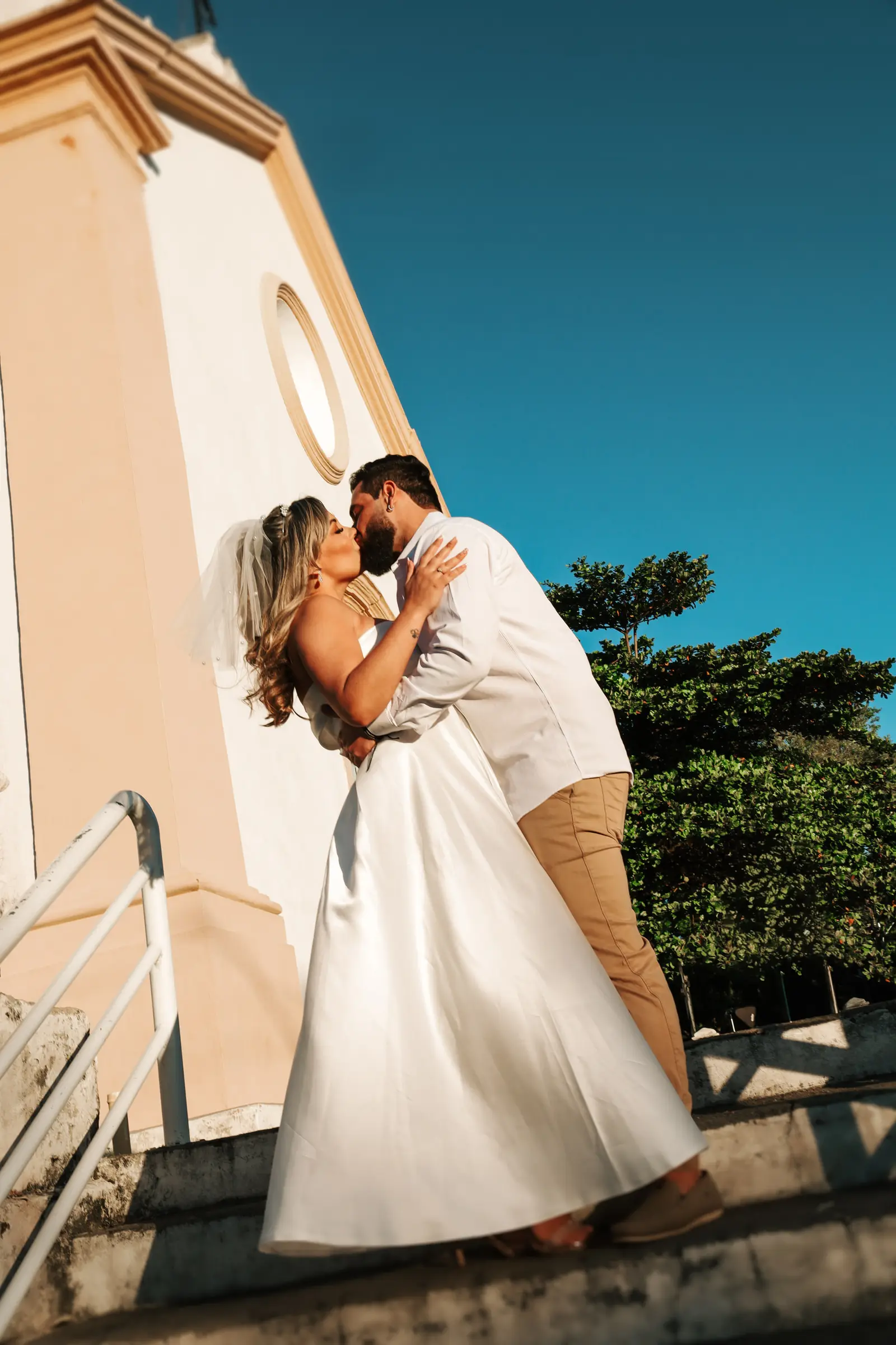 Noivos se beijando na escadaria da igreja
